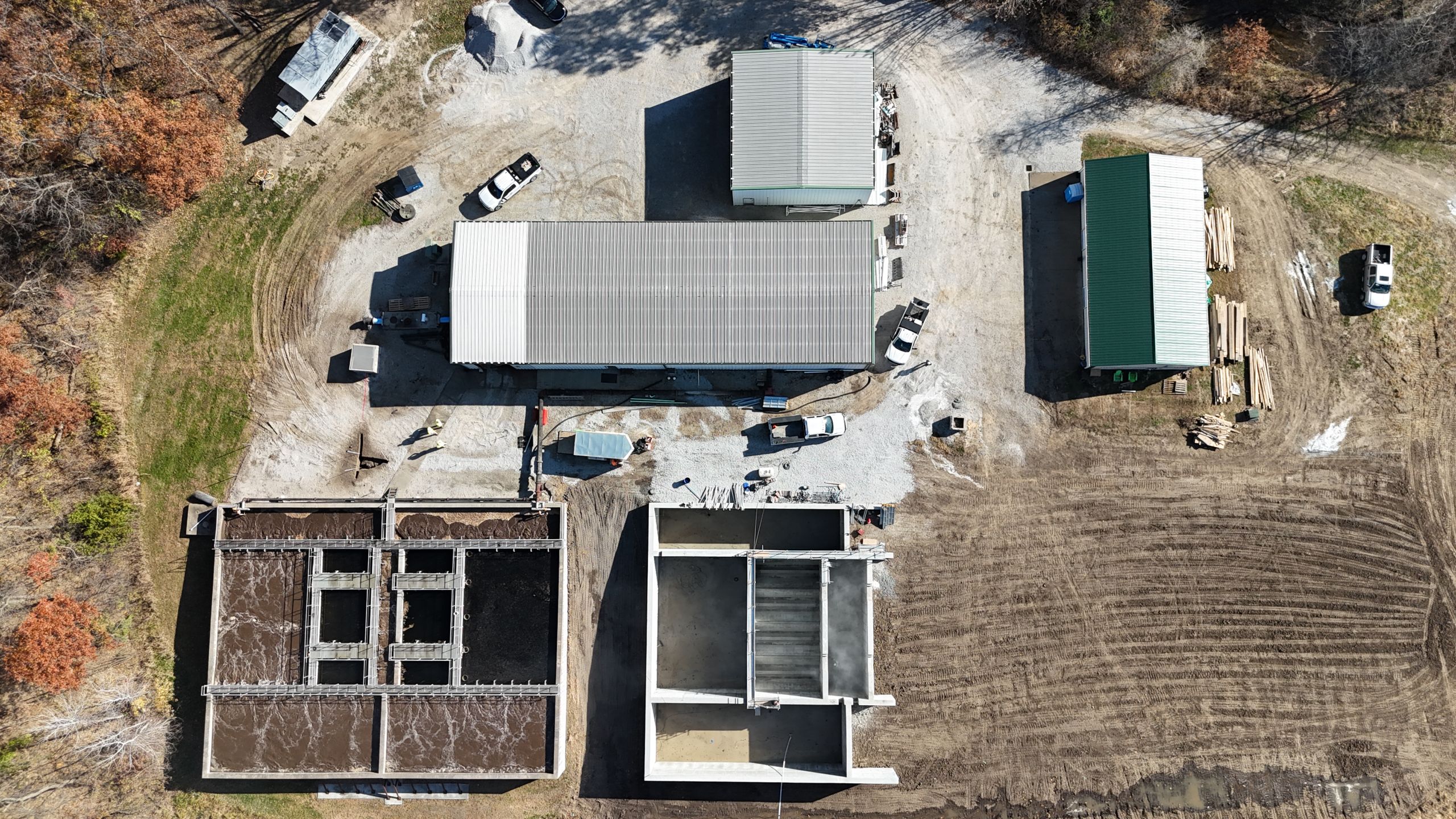 Overhead drone shot of an industrial facility construction site featuring newly poured concrete basins and metal warehouse buildings by Havens construction.